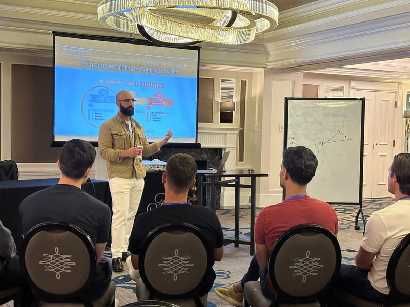 Ayman Al-Abdullah presenting his 9 Steps to 9 Figures slide to a small seated audience