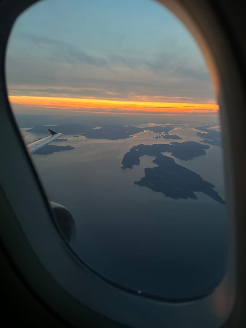 A sunset view of islands and water seen through an airplane window